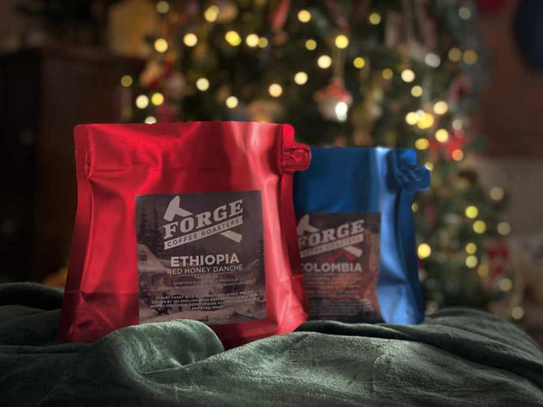 two bags coffee,  one ethiopia, one colombia, standing atop a green velvet cloth, in front of a dappled light background