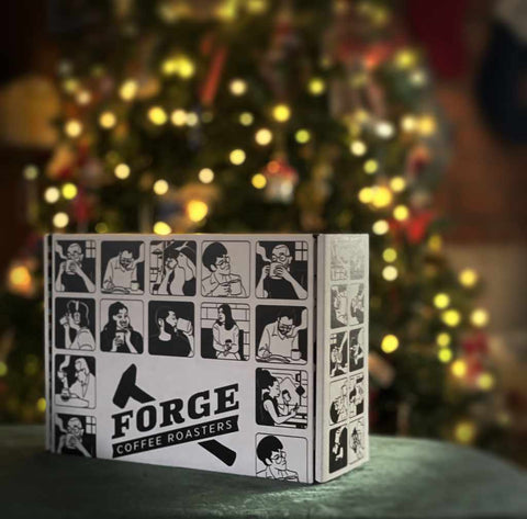Box with 'Forge Coffee Roasters' branding in front of a decorated Christmas tree.