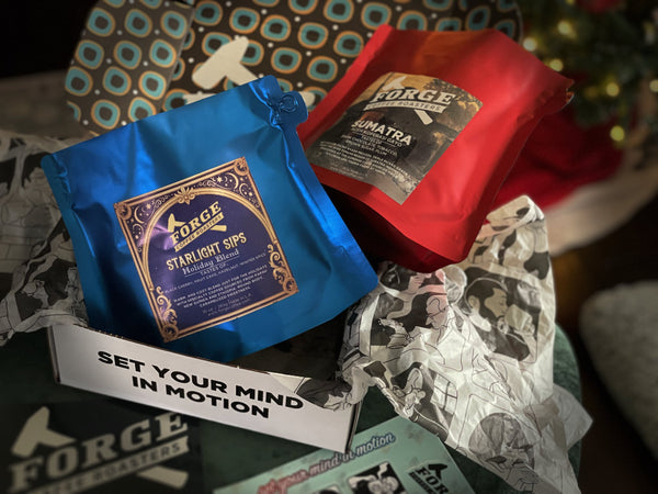 Two coffee packages from Forge Coffee, one blue and one red, with visible branding and text.